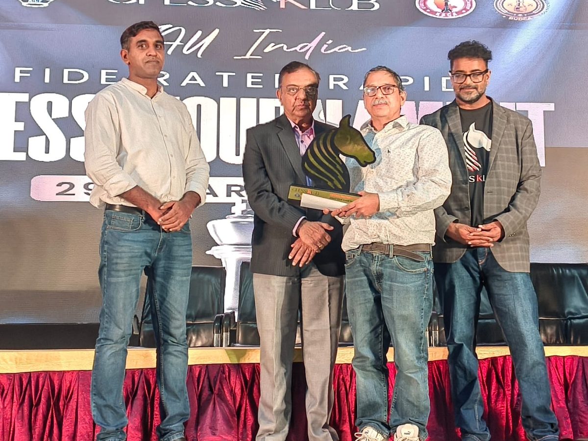 Namboothiri K N receiving the veteran category trophy on stage at the All India FIDE Rated Rapid Chess Tournament, March 2026
