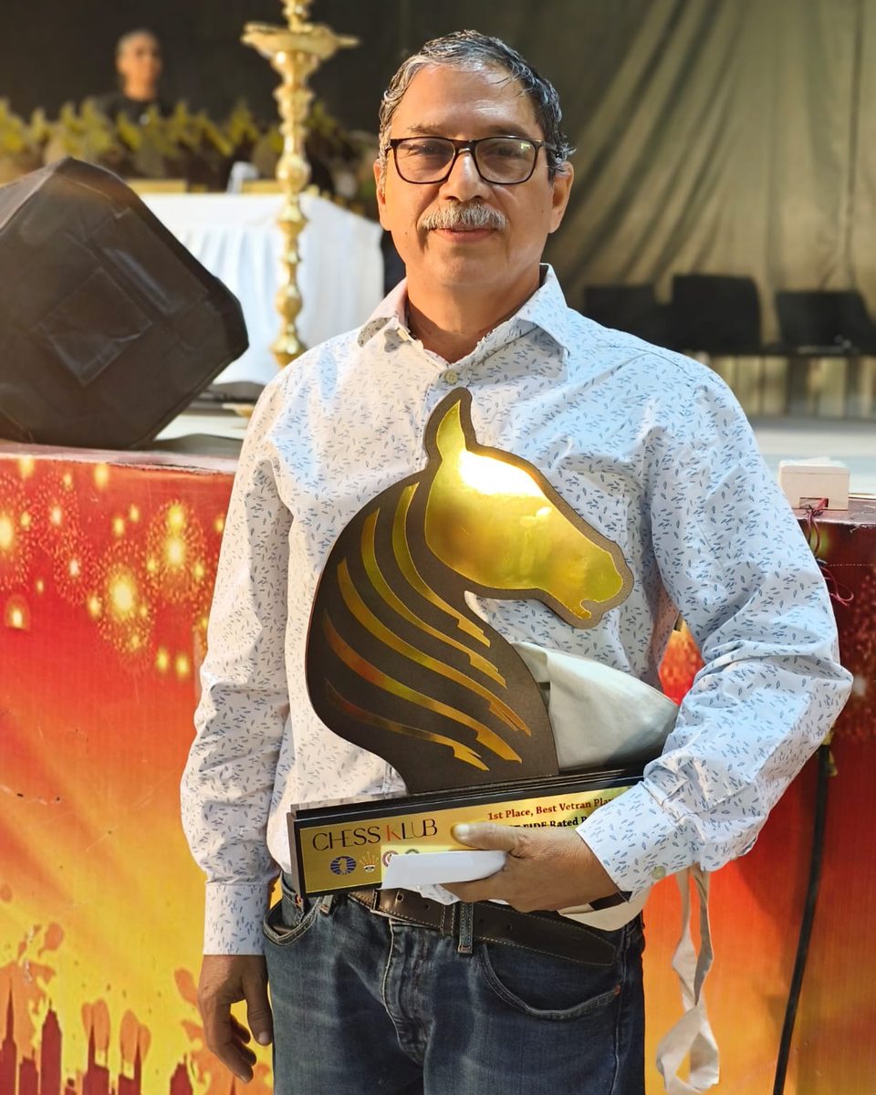 Chess coach Namboothiri K N holding his 1st Place Best Veteran Player trophy